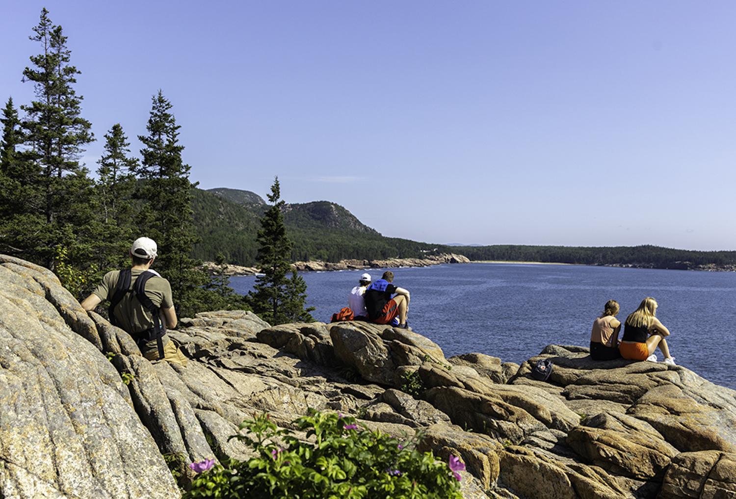 Visitors sit watching the ocean at Otter Cliffs along Park Loop Road in Acadia National Park. (Photo by Lily LaRegina/Friends of Acadia)