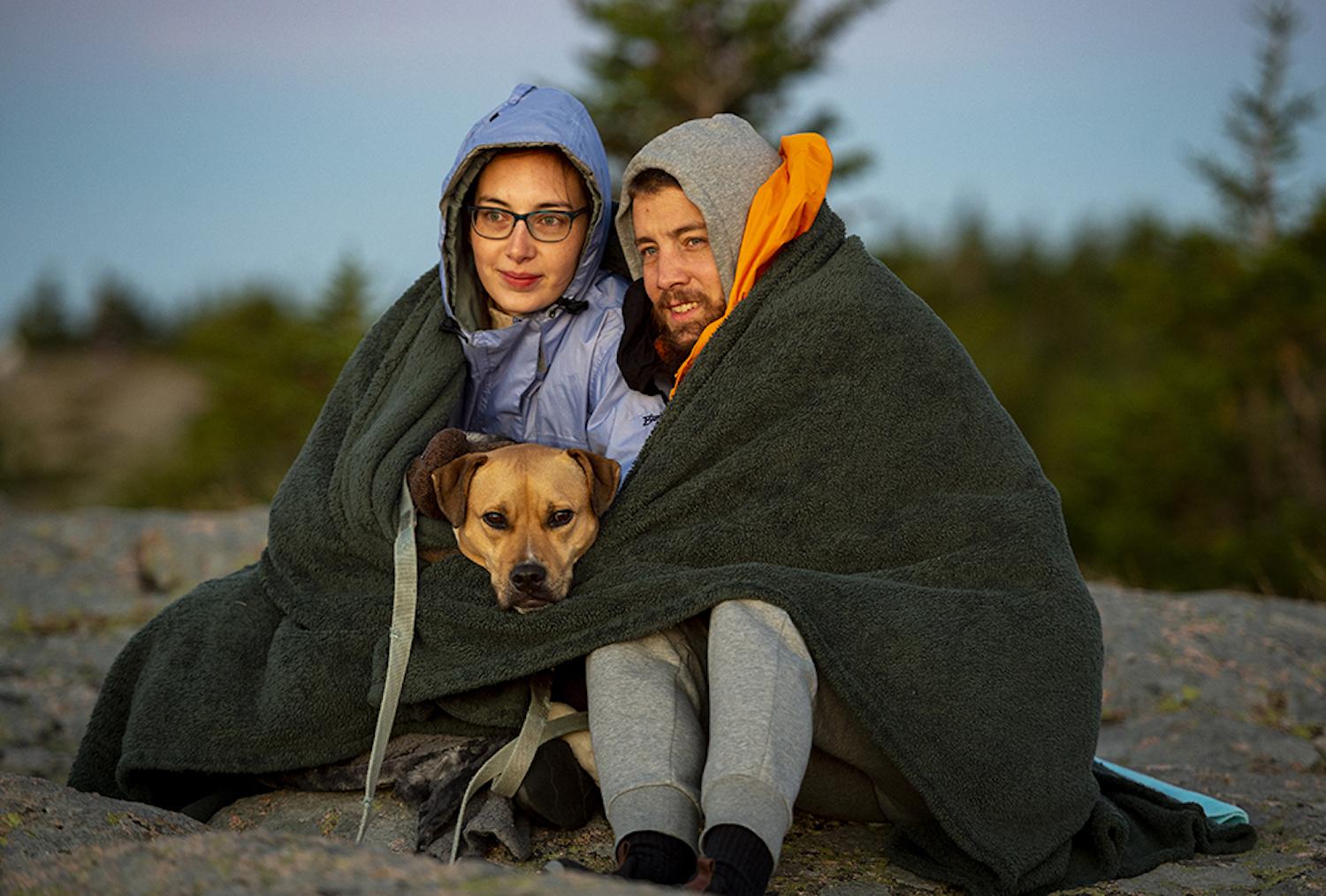 Park visitors Taylor Thompson and Russell Bloom wrap themselves and their dog Chloe in a blanket to stay warm while waiting for the sunrise on top of Cadillac mountain in Acadia National Park. (Photo by Will Newton/Friends of Acadia)