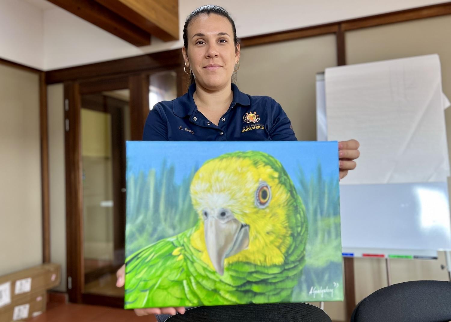 At the Aruba National Park Foundation office, communications and marketing manager shows off a Lora painting by local artist Armando Goedgedrag.