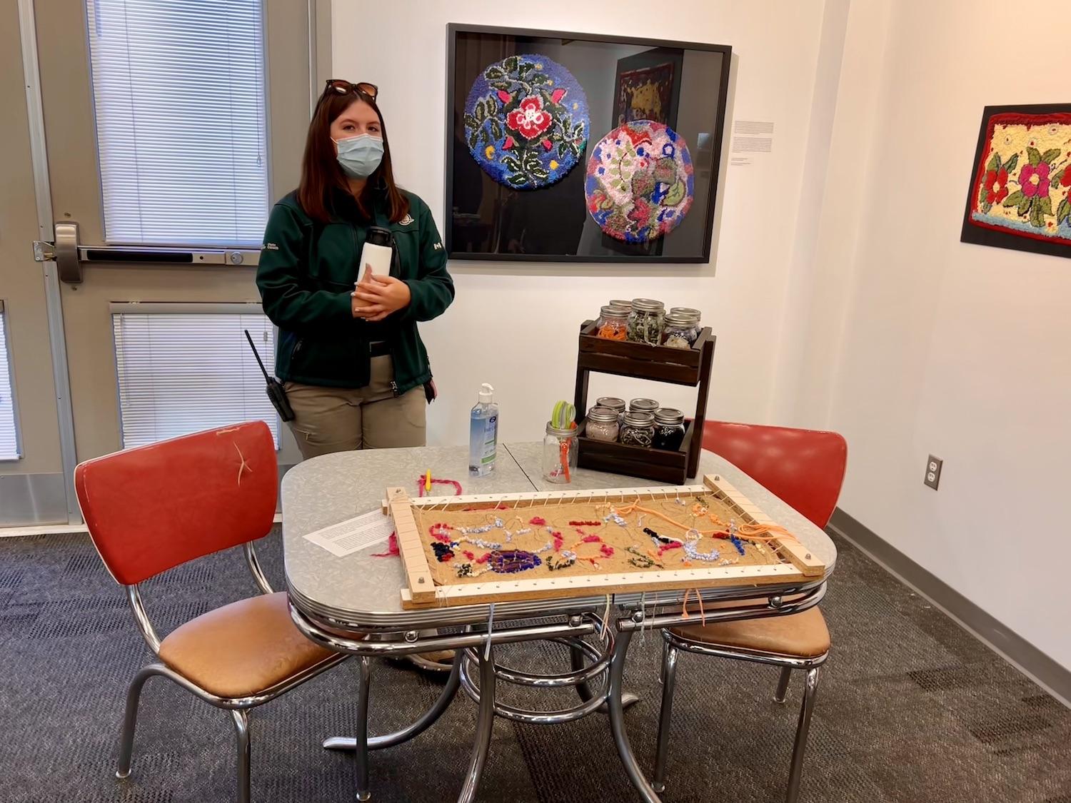 At the rotating exhibit room in September, heritage interpreter Jacelyn Perret lets visitors try rug hooking.