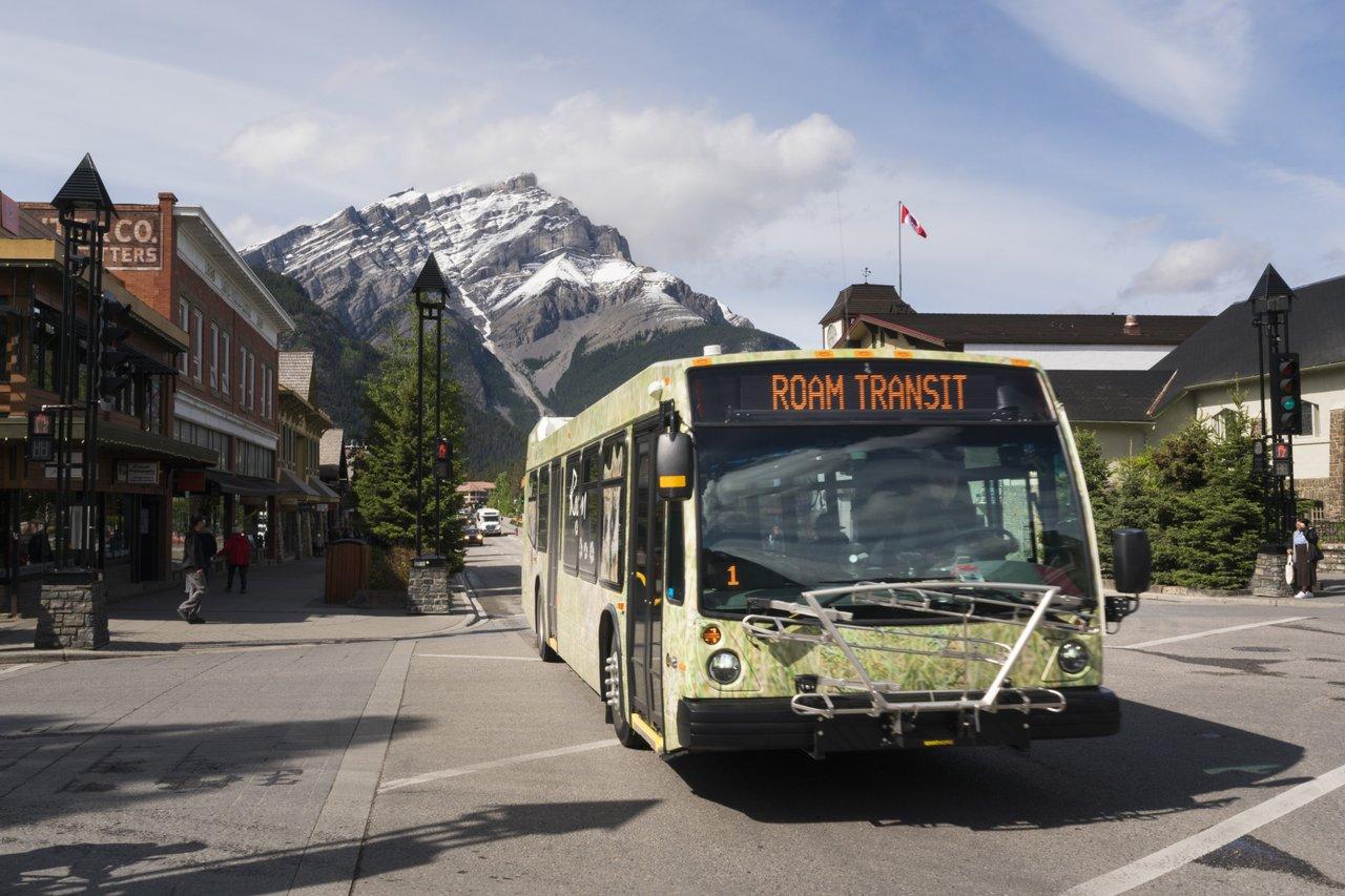 A Roam Public Transit bus is shown on Banff Avenue in front of Cascade Mountain.