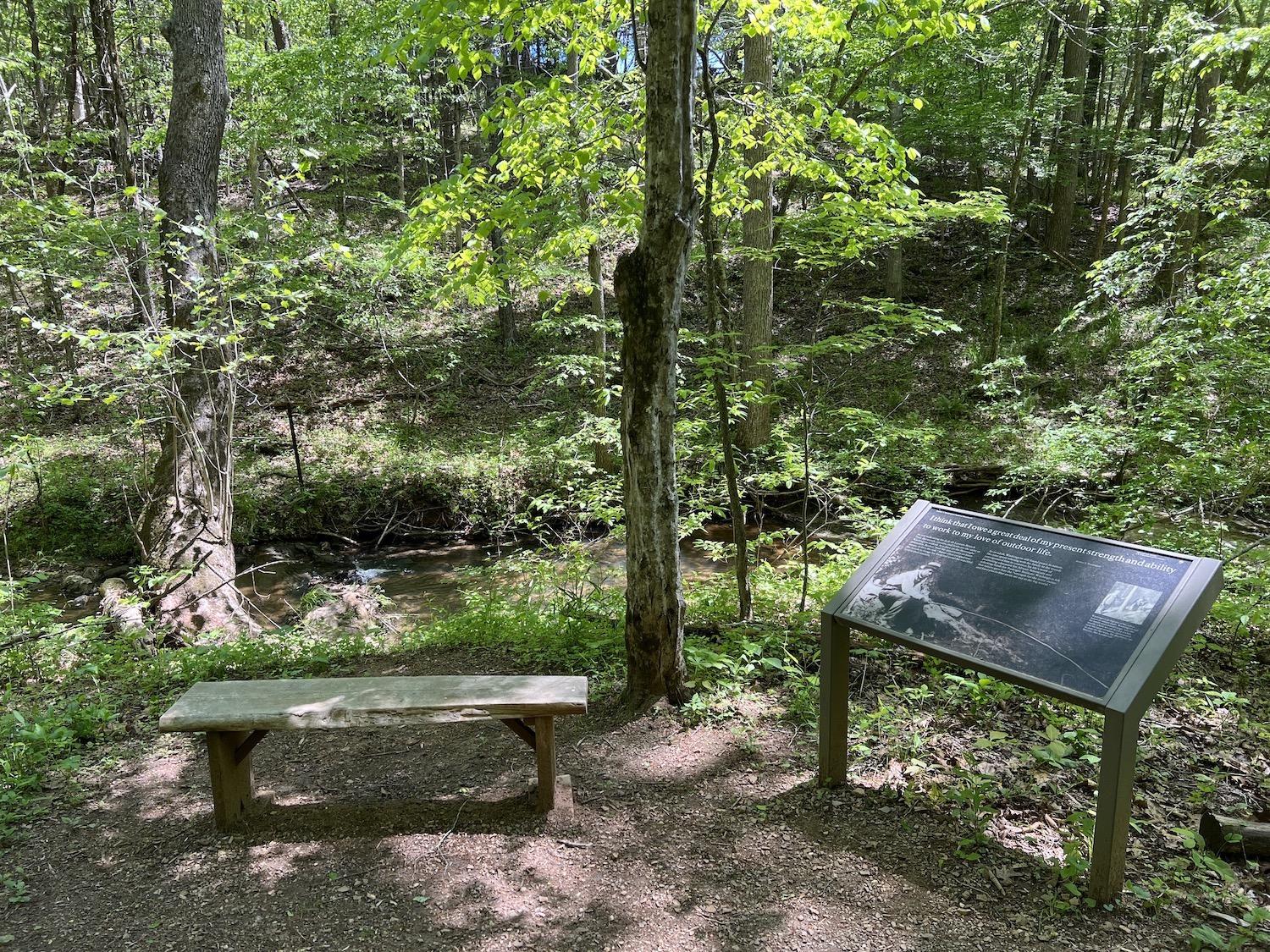 An interpretive panel and bench along Jack-O-Lantern Branch Trail at Booker T. Washington National Monument in Virginia.