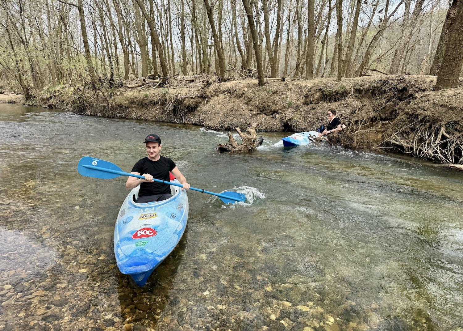 One kayaker makes it past the tree root while the other gets caught on it and has to abandon her water-filled boat.