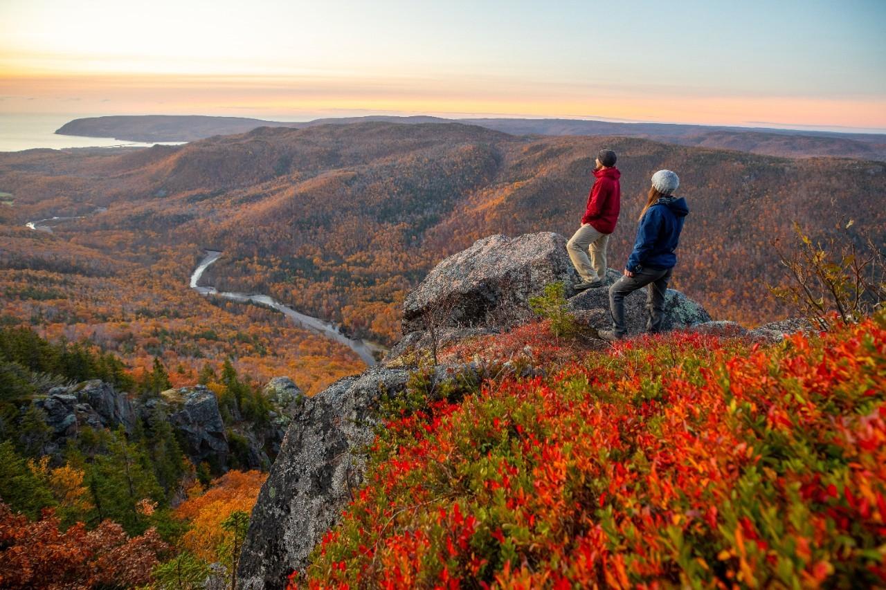 Two visitors enjoy a scenic viewpoint during the fall hiking season on the Franey Trail in Cape Breton Highlands National Park in Nova Scotia.