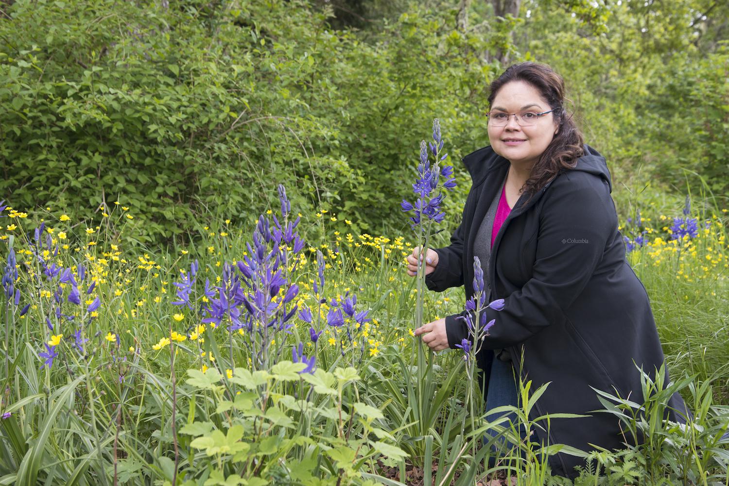 Songhees Nation Knowledge Holder Cheryl Bryce shows off culturally significant camas in the Garry Oak Learning Meadow.
