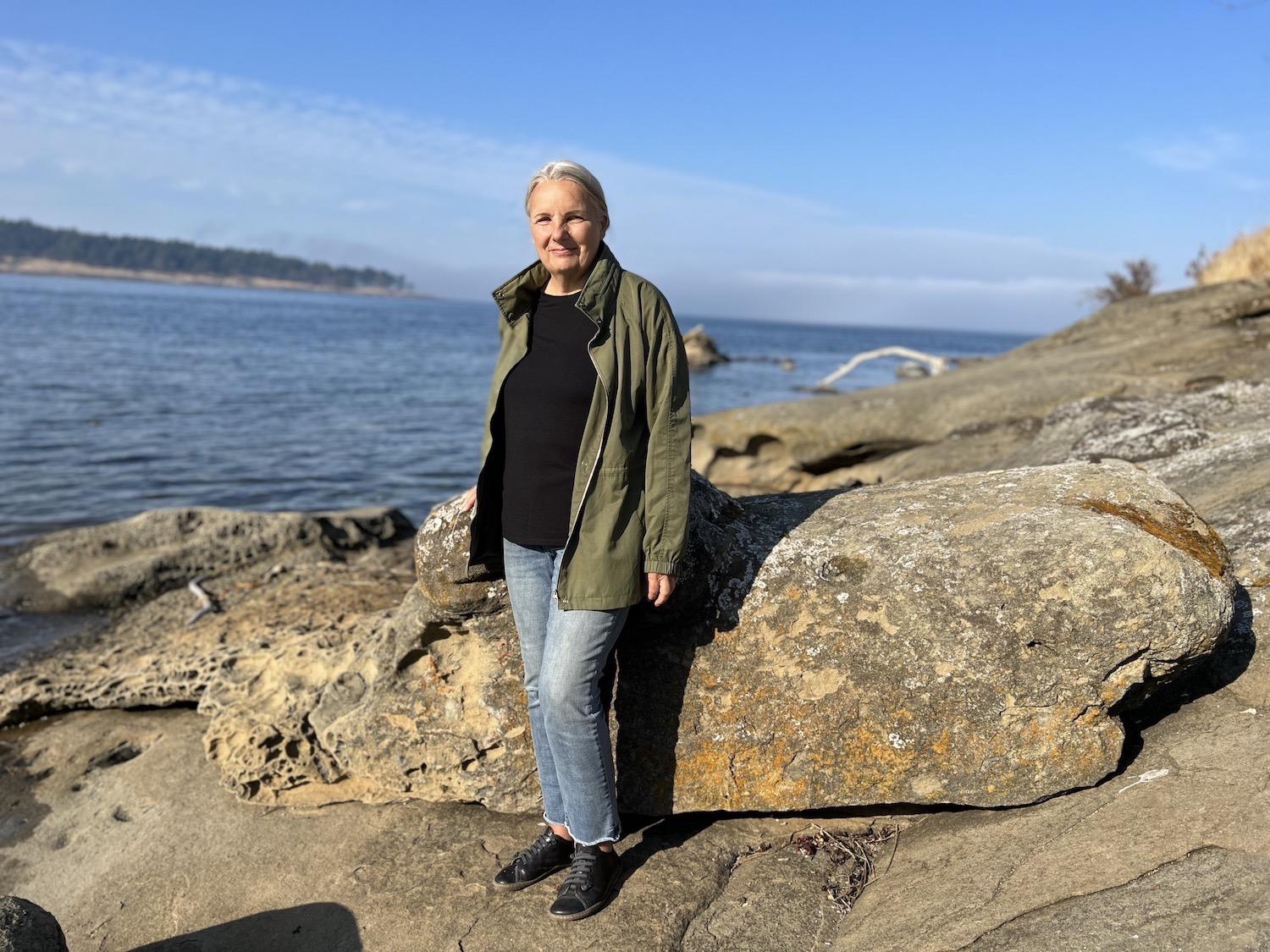 Maureen Welton, vice-chair of the Saturna Island Marine Research and Education Society (SIMRES), stands by rocks with tafoni erosion patterns.