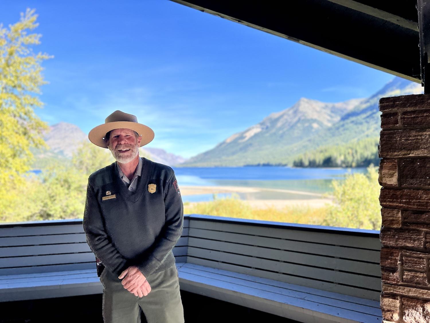 Glacier National Park interpretive ranger Frank Jahn stands in the Snowflake Pavilion at Goat Haunt in front of a landscape so beautiful that it looks like a painting.