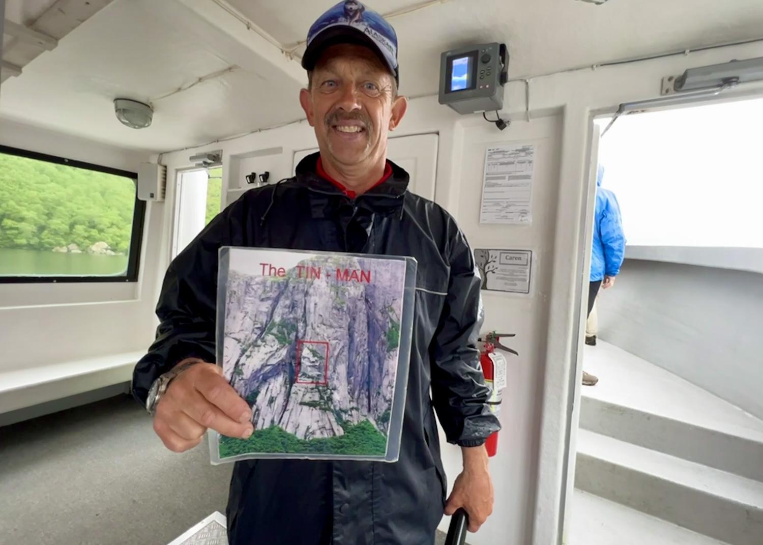 BonTours guide Glen Laing shows a laminated photo while explaining how to spot the Tin Man in the rock cliffs along Western Brook Pond.