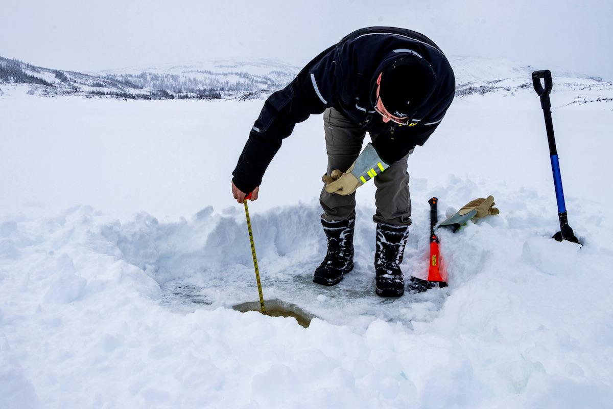 A Gros Morne visitor tests the ice for trout fishing.