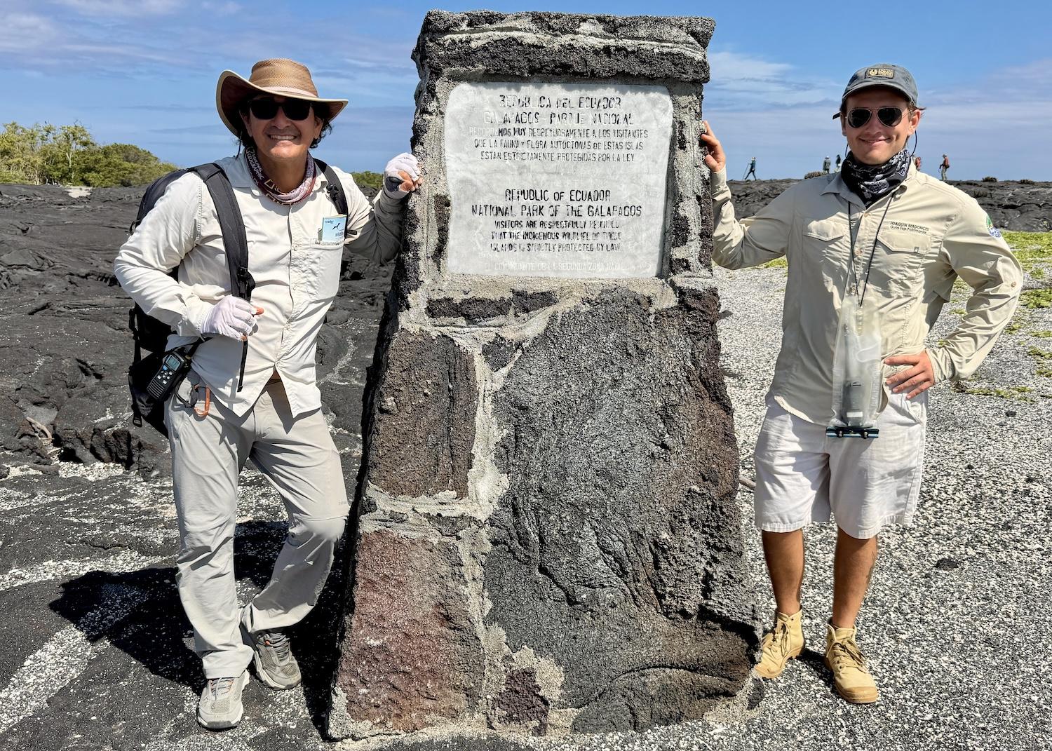 On Fernandina Island, naturalist guide Celso Montalvo stands by a national park sign with Joaquin Berdonces, who is finishing his Galápagos National Park naturalist guide course with an internship. On Fernandina Island, naturalist guide Celso Montalvo stands by a national park sign with Joaquin Berdonces, who is finishing his Galápagos National Park naturalist guide course with an internship.