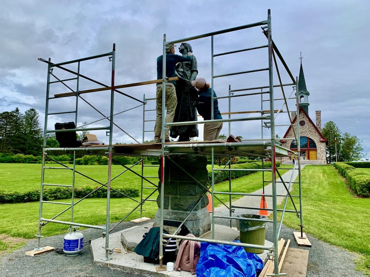 Parks Canada conservators Antoine Pelletier and Carolyn Savage work on the Evangeline statue at Grand-Pré National Historic Site.