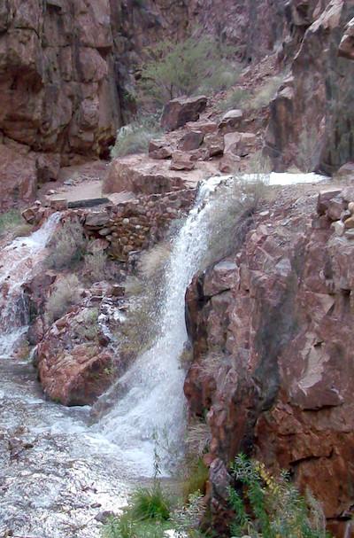 Water rushing out of the Transcanyon Waterline from a break in the pipe in 2014, along the North Kaibab Trail with the water flowing down into Bright Angel Creek. The water pipeline is buried below the surface of the trail in this area.