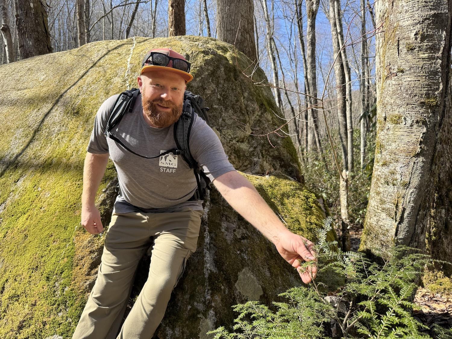 On Middle Prong Trail, Clayton LaPrees of Smoky Mountain Guides stands by a mossy rock.