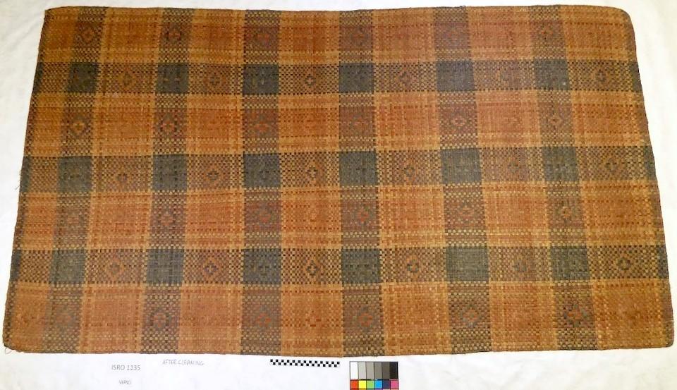 Handwoven mat made of dyed cedar bark strips; black, red, and natural plaid check pattern with medicine eye design.  The mat was possibly crafted by Tchi-ki-wis Linklater in 1930. The mat is eight feet long and four feet eight inches wide/NPS