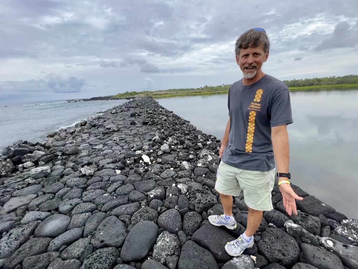 Ranger Jon Jokiel stands on the ancient stone wall at the Kaloko Fishpond.