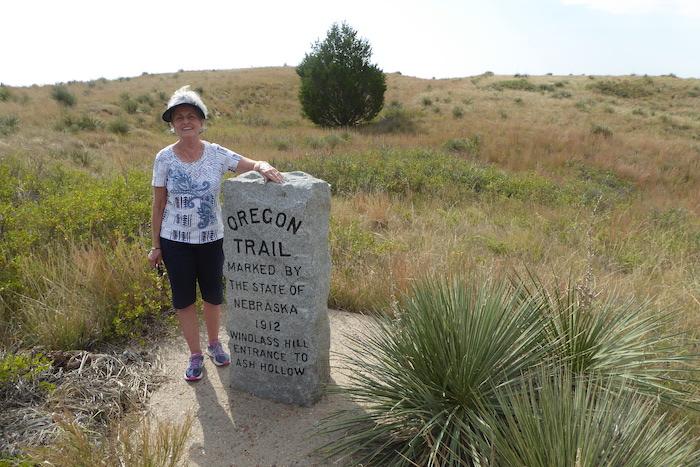 Author Kay Scott beside an Oregon Trail marker on a trail near the top of Windless Hill/David Scott