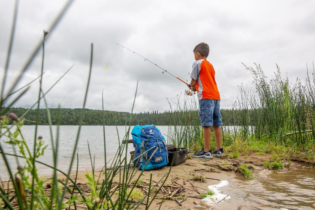 A boy fishes from shore in Prince Albert National Park in 2019.