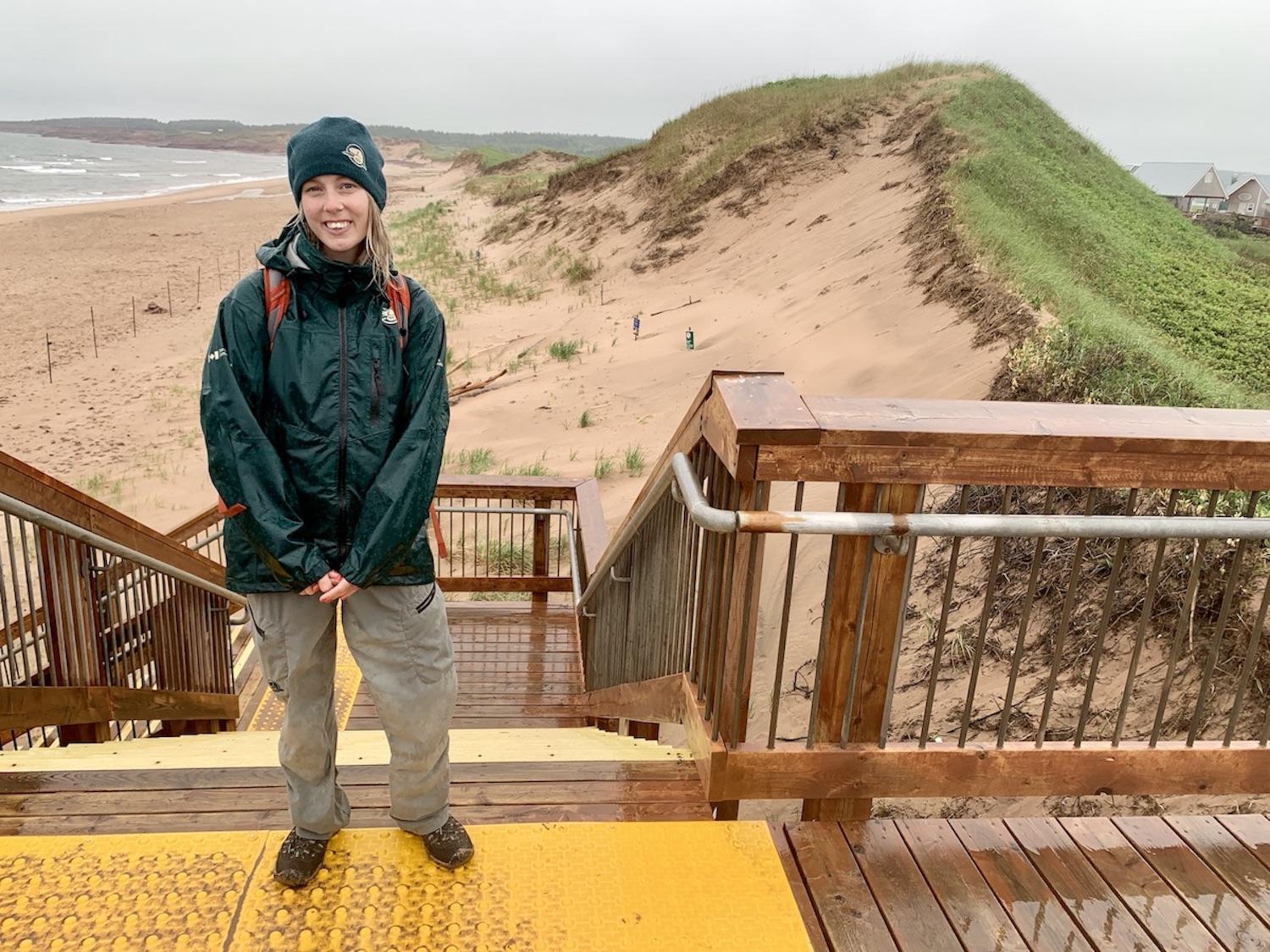 Lindsey Burke, a Parks Canada resource management officer with the P.E.I. Field Unit, stands in front of dunes protected by a boardwalk, fencing and signs. 