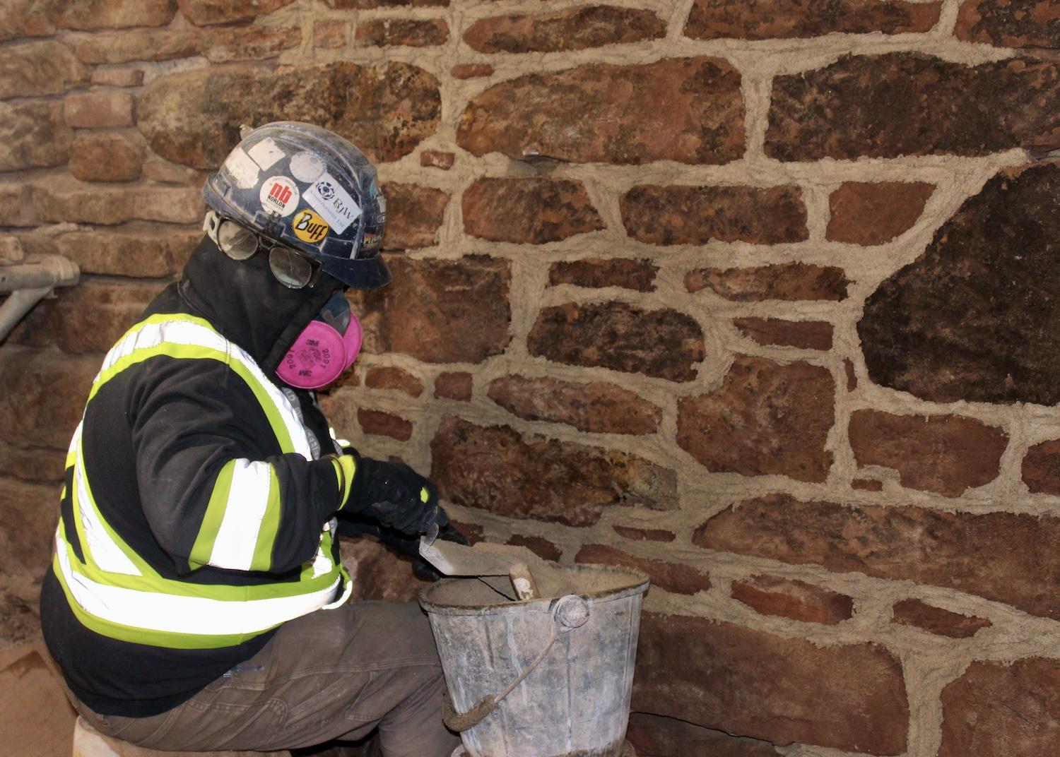 A stonemason works on stones, below grade of Province House National Historic Site.