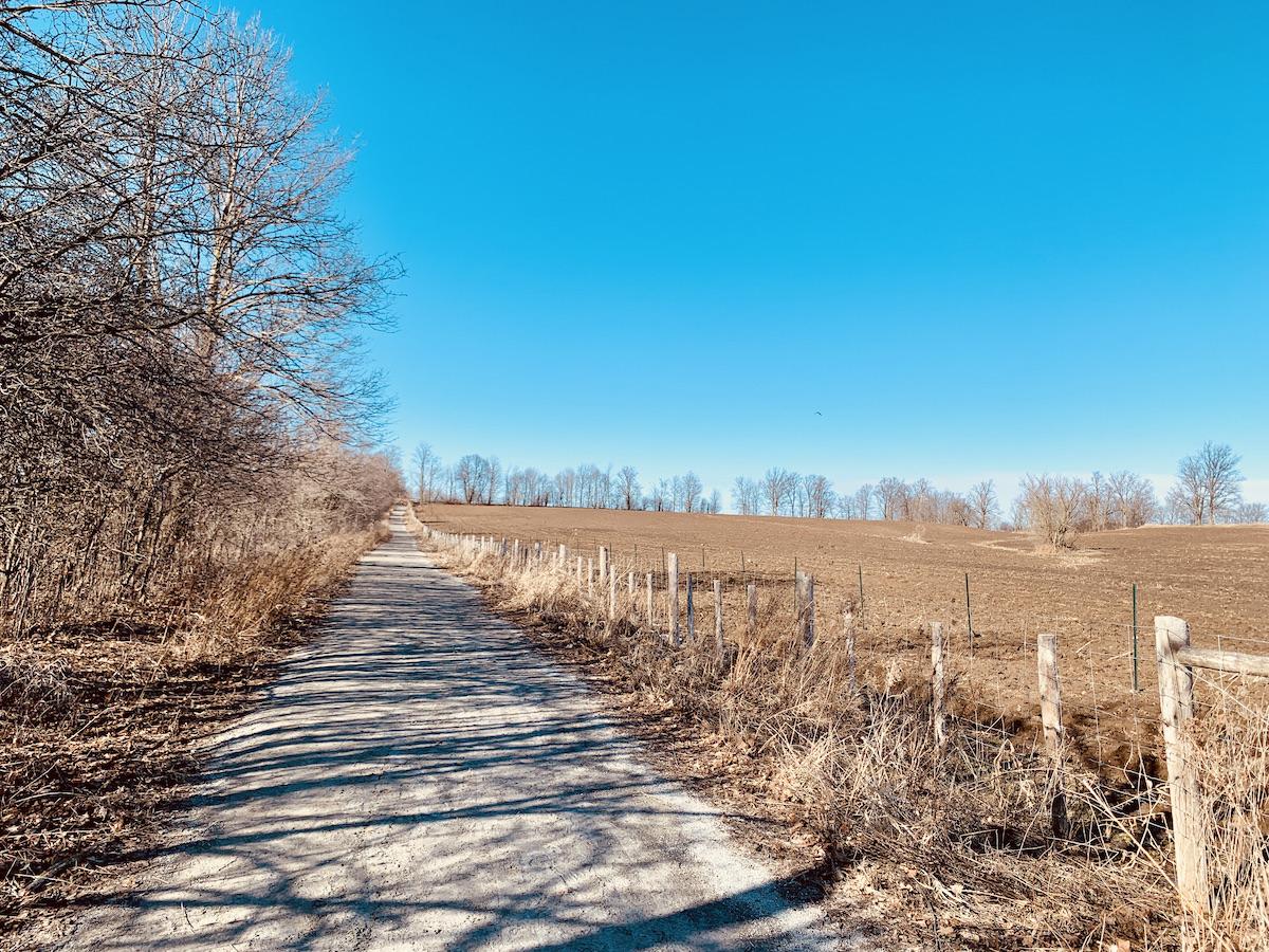 A hiking path meanders between fenced farm fields.