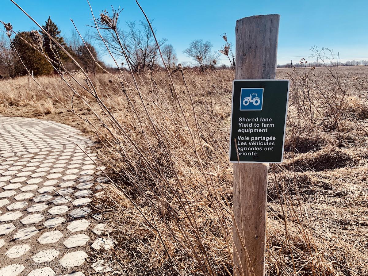 A sign asks hikers to share the path with farm equipment.
