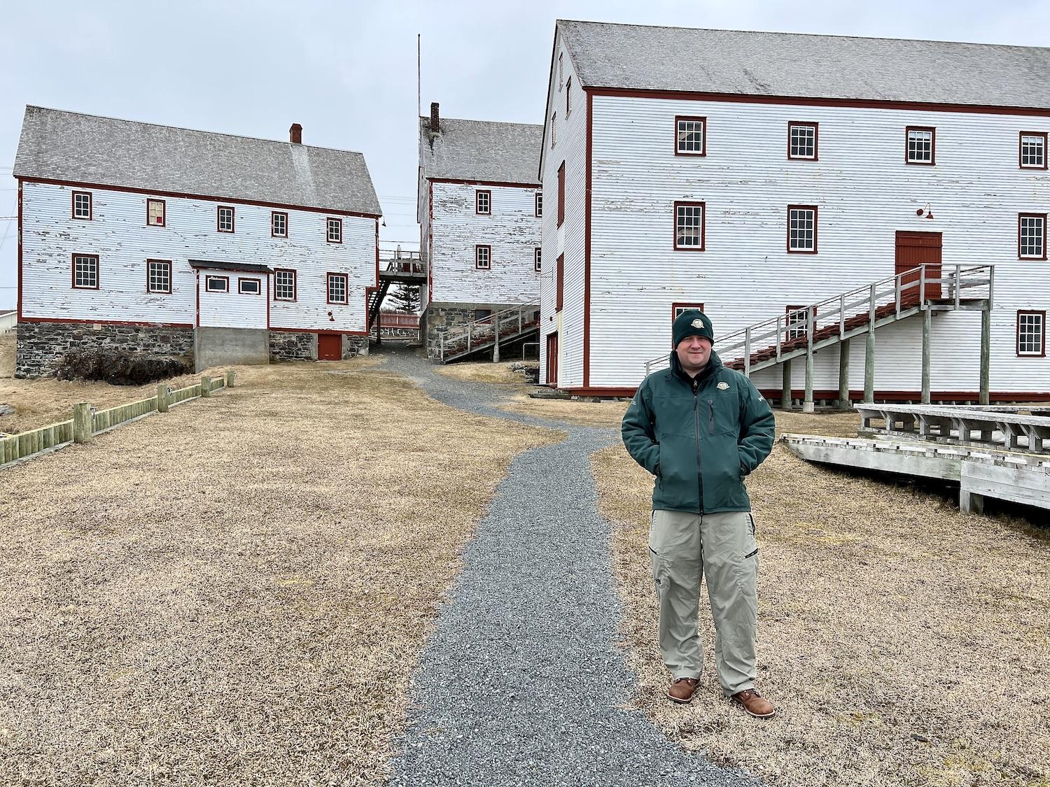 Parks Canada's Jonathan Harrison stands by the white clapboard buildings at Ryan Premises National Historic Site in May before the site opened for the season.