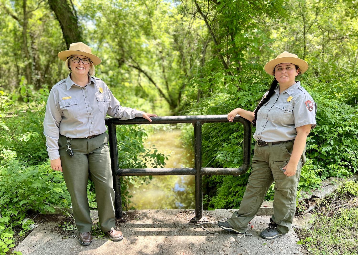 San Antonio Missions Superintendent Christine Jacobs and Ranger Destiny Gardea stand over an acequia at the Espada Aqueduct.