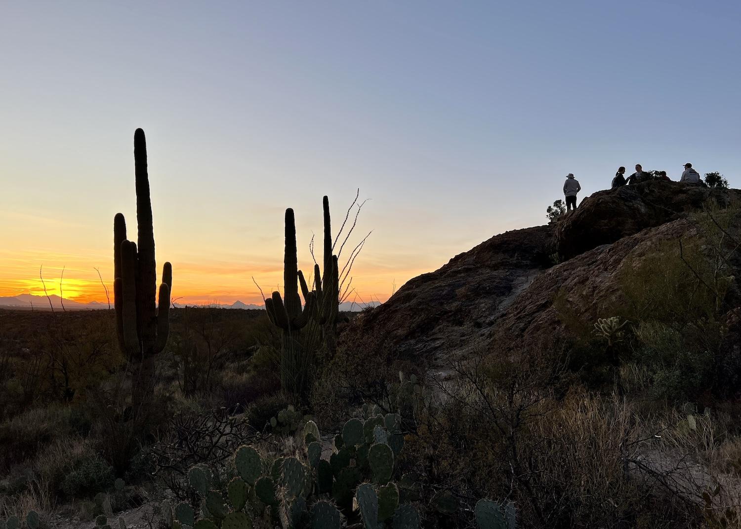 People gather on the Javelina Rocks in Saguaro National Park to watch the sun set over Tucson.