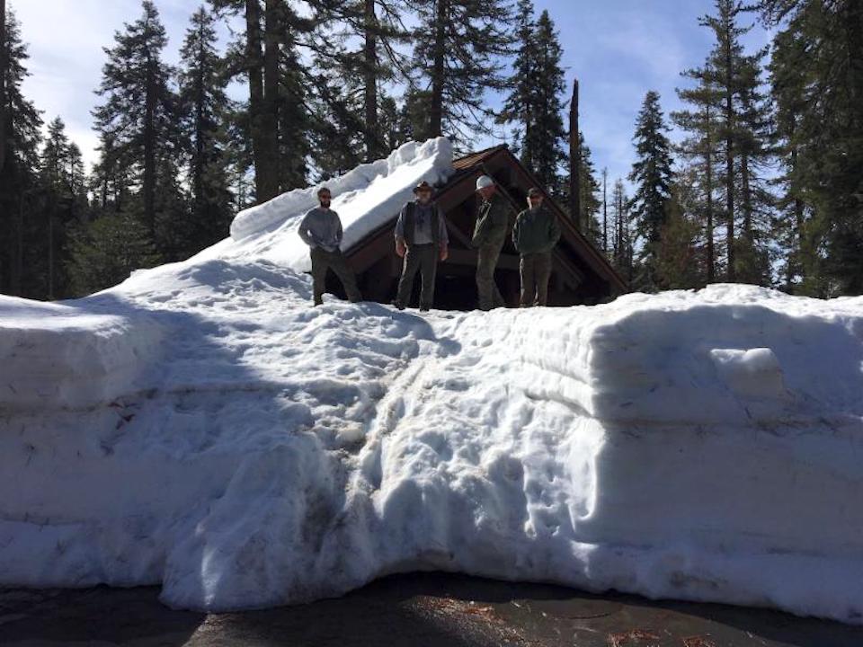 Rangers stand on the snow at the Sherman Tree comfort station/NPS