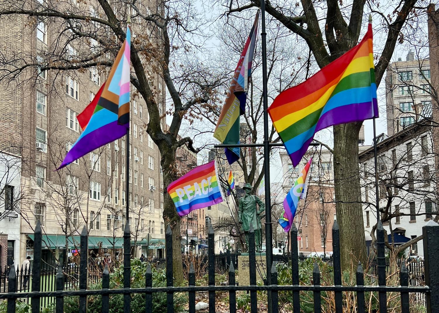 At Stonewall National Monument, various pride flags flutter in front of the statue of a Civil War general.