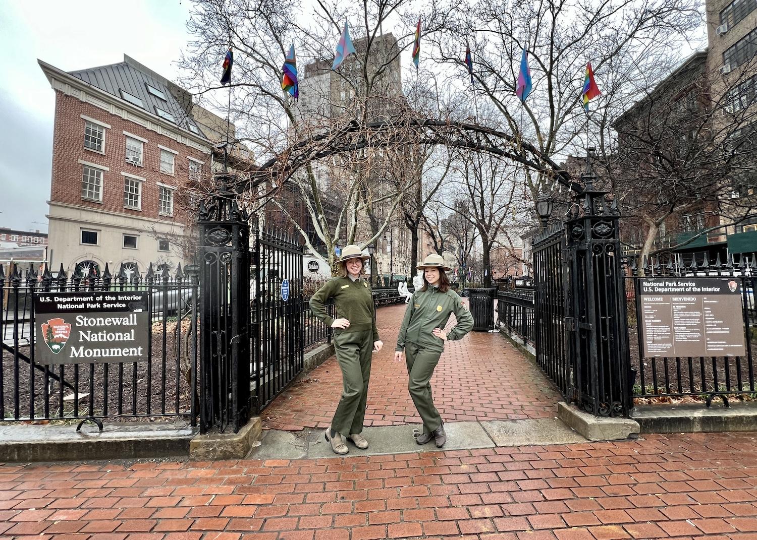 Supervisory ranger Callie Tominsky and lead ranger Julie Burna stand at the entrance arch to Stonewall National Monument.