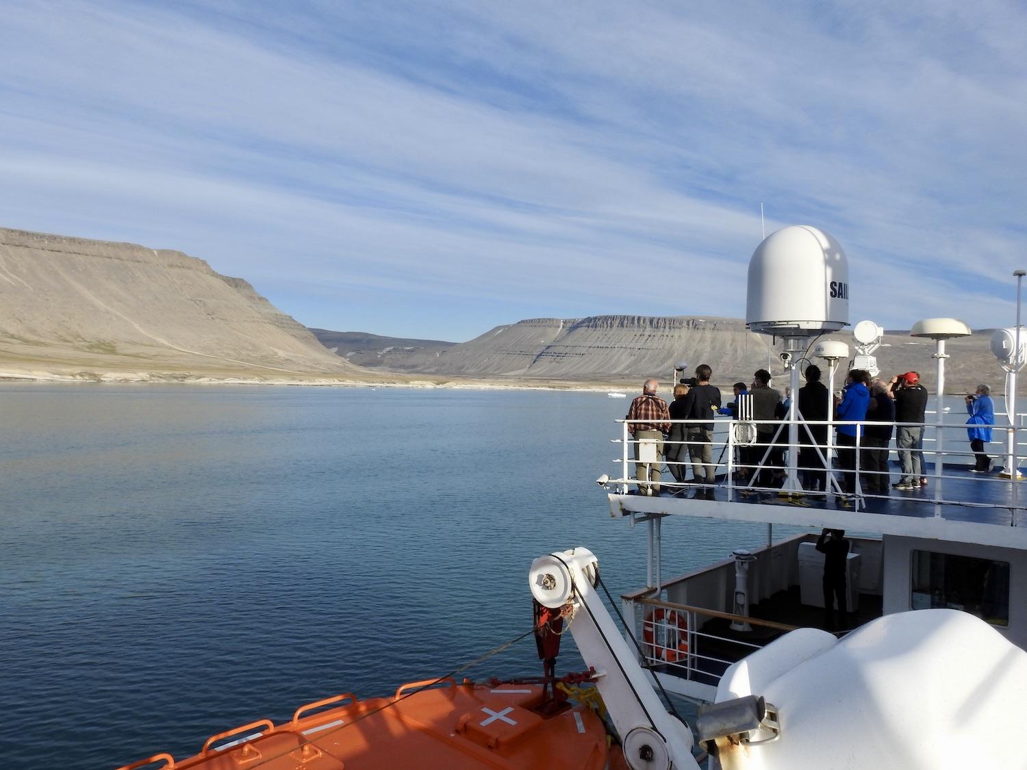 Adventure Canada guests gather on deck to see polar bears walking on the land at Croker Bay in 2022.