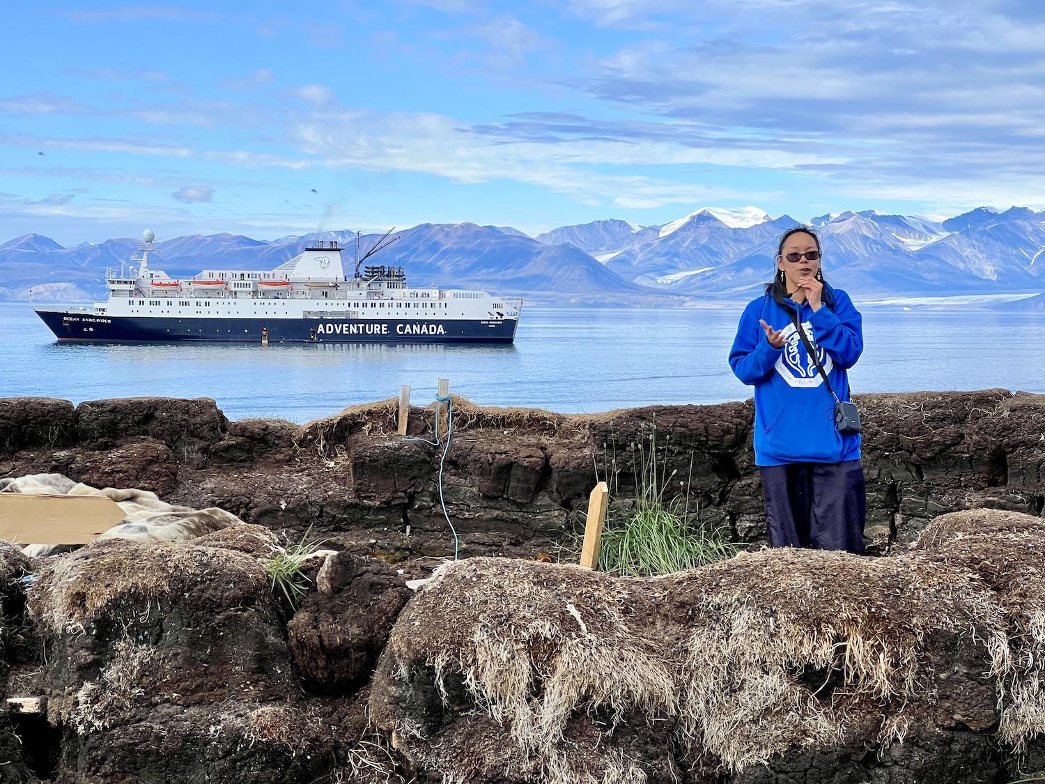 In 2022, Pond Inlet tour guide Georgina Pewatooalook shows Adventure Canada guests a sod house while the Ocean Endeavour waits in the proposed Tallurutiup Imanga National Marine Conservation Area.
