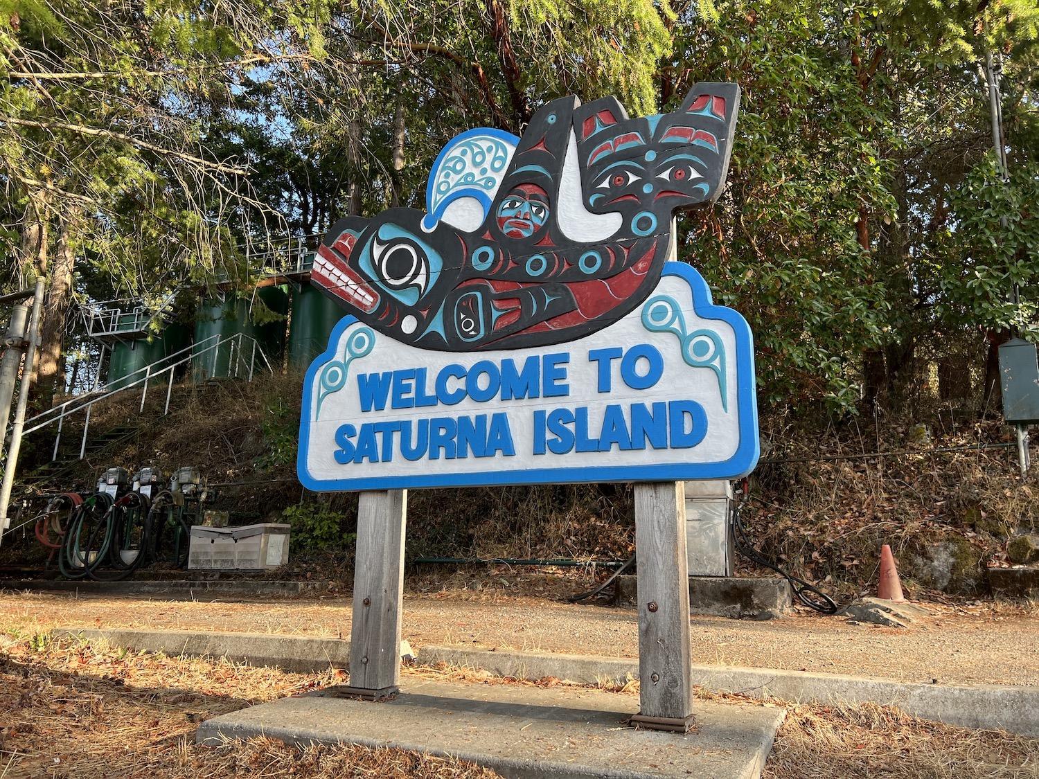 The "Welcome to Saturna Island" sign features a carving of an orca.