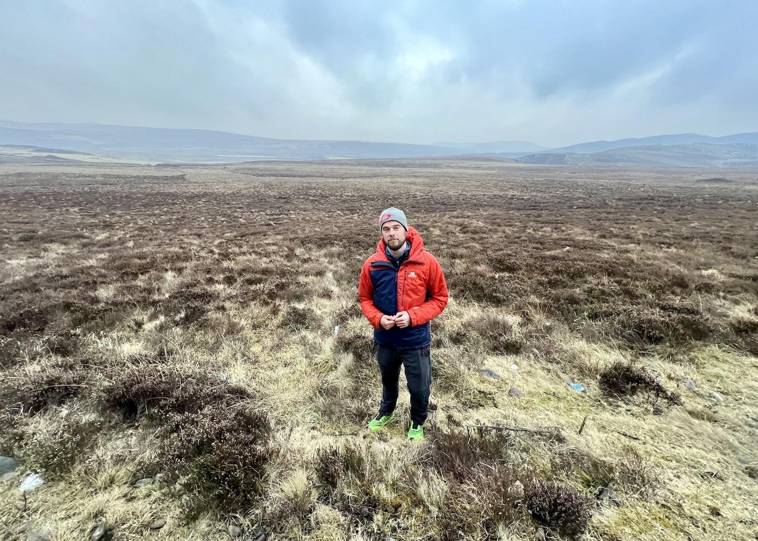 Wilderness Scotland guide Joe Mann stands in front of grouse moorland just outside of Cairngorms National Park in Scotland.