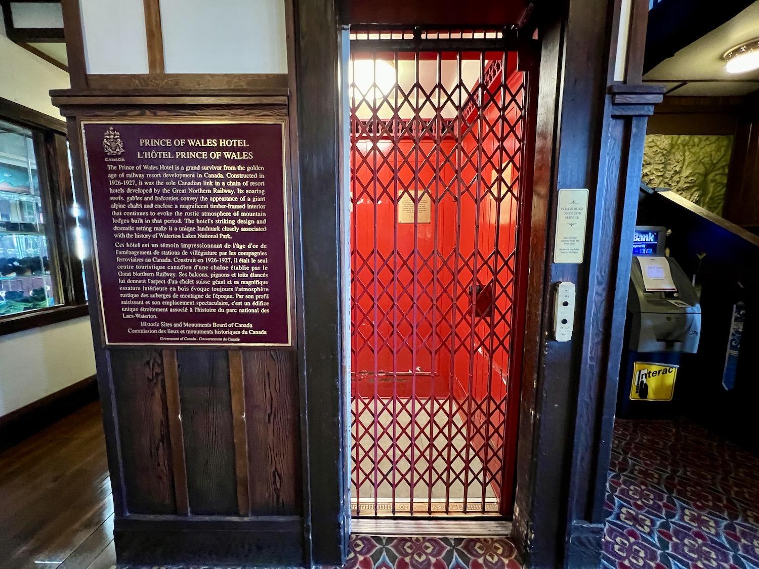 A plaque for Prince of Wales Hotel National Historic Site stands in the hotel's lobby by the vintage elevator.