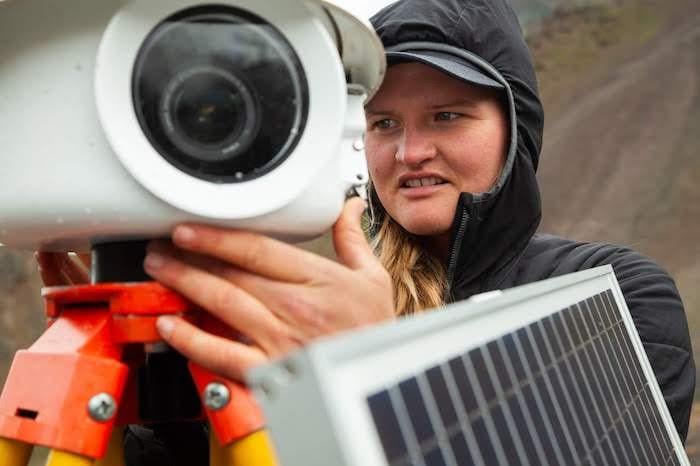 Lia Lajoie inspects an autonomous timelapse camera installed in 2019 to monitor the remains of Flat Creek glacier and the valley headwall for any future detachments and other changes. Due to precautions taken because of COVID-19, it is still unknown when 