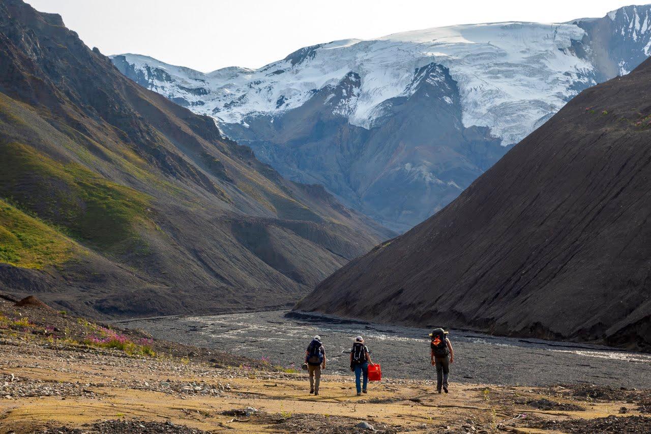 Matthias Leopold, Mylène Jacquemart, and Lia Lajoie (l-r) hike back to camp after a nine hour day in the valley bottom investigating the deposits left by the Flat Creek glacier detachments. Flat Creek glacier (or what remains of it) is the left-most glaci