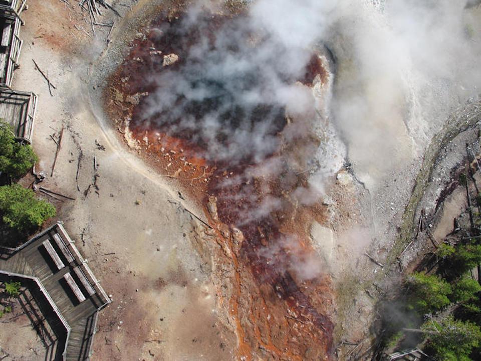 Aerial view of Echinus Geyser, which exhibits irregular behavior, sometimes erupting regularly for months, and then ceasing altogether. Gas emissions from the geyser are mostly steam and occur whether the geyser is erupting/Brit Graham Wall