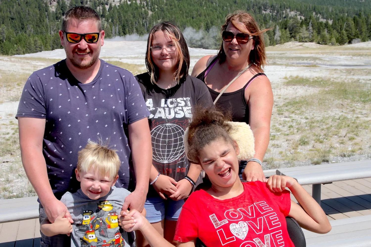 Yellowstone National Park tourist Liz Adkins, upper far right, poses with her family on the Old Faithful boardwalk in August 2023. (Mike Koshmrl/WyoFile)