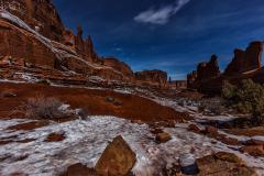 Winter ice and red rock of Park Avenue at midnight in Arches National Park in Utah