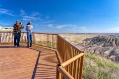 Two people on a viewing platform looking out to the distant formations in Badlands National Park in South Dakota