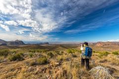 A photographer with backpack and long lens photographing the expansive view at Sotol Vista in Big Bend National Park
