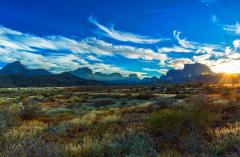 Sunset over the dry landscape of the Chihuahuan Desert and Chisos Mountains beneath a blue sky wtih white wispy clouds, Big Bend National Park