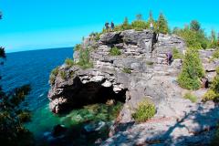 A rocky hill over a cave and shallow grotto covered with blue-green water, Bruce Peninsula National Park