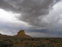 Storm clouds hovering over a tall butte landform at Chaco Culture National Historical Park