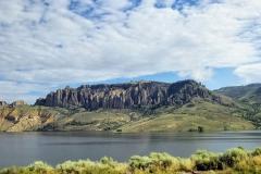 A view of the Dillon Pinnacles on the other side of the water at the Blue Mesa Reservoir on a day full of fluffy clouds at the Curecanti National Recreation Area