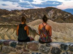 The blurred backs of two young women sitting on the stone barrier waiting for sunrise at Zabriskie Point, Death Valley National Park