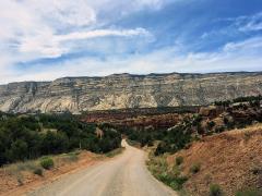 Echo Park Road winds away towards geologic features of many colors towering in the distance in Dinosaur National Monument