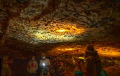 several masked people standing around a national park intern in a cave room with sooty words and names on the ceiling in Lehman Caves at Great Basin National Park